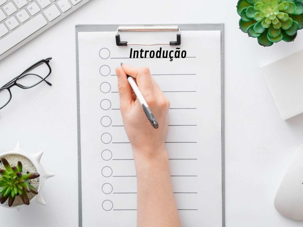 Pessoa escrevendo a introdução do mestrado em um caderno com plantas ao redor, destacando a importância de uma boa introdução do teu mestrado.