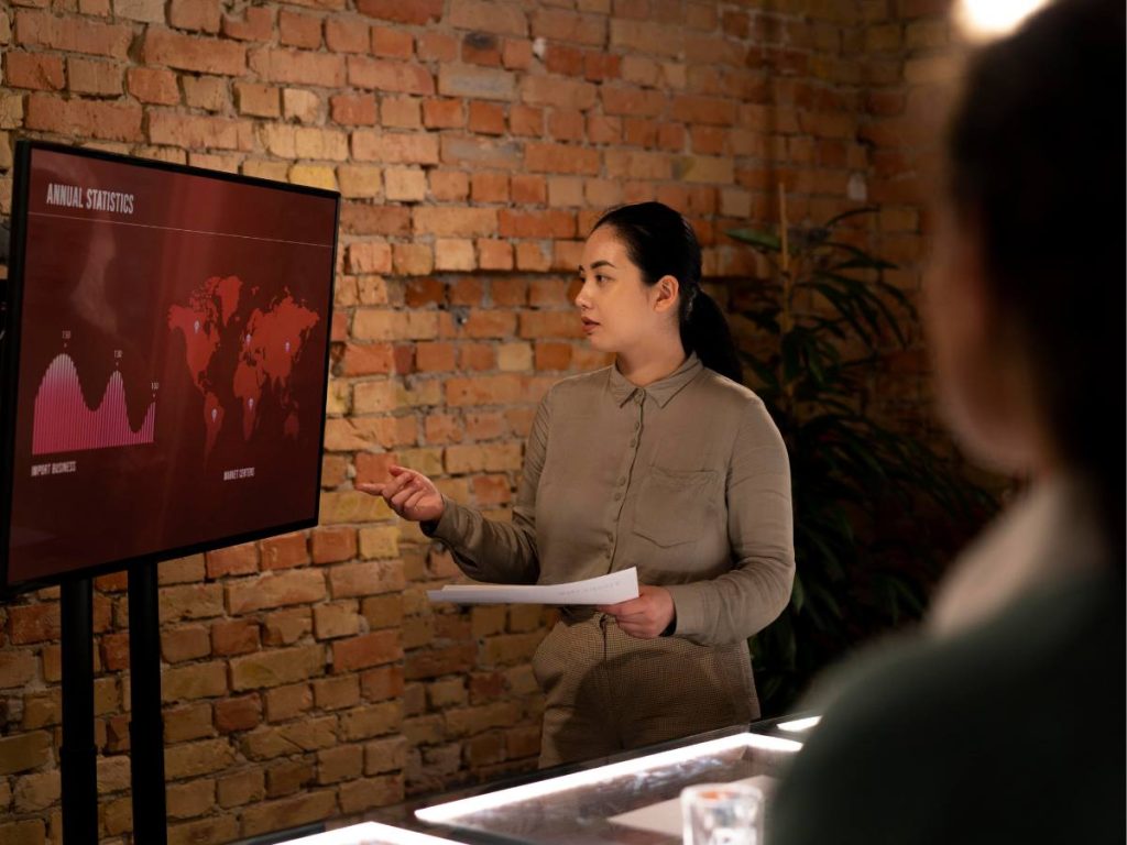 Estudante apresentando sua defesa de mestrado em frente ao comité avaliador, ilustrando a defesa de uma tese acadêmica com clareza e confiança.