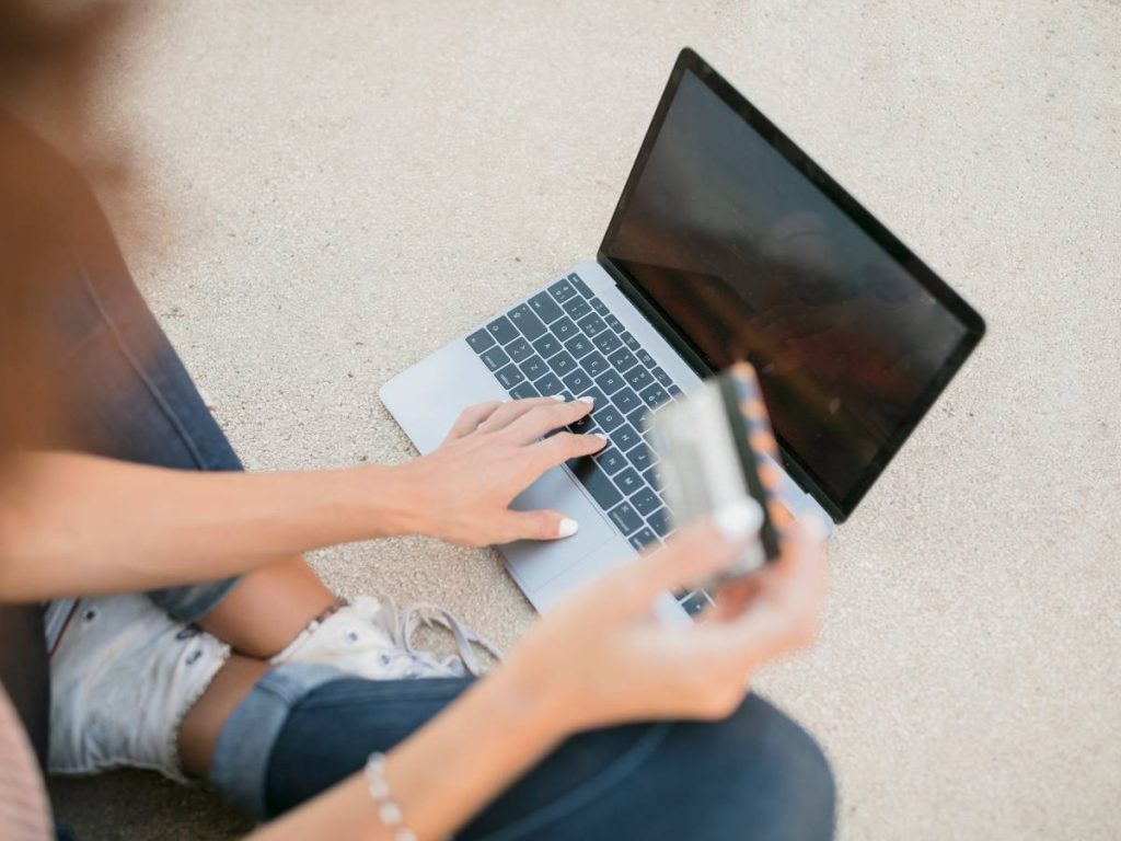 Estudante trabalhando em um projecto de mestrado online com laptop e materiais de estudo.