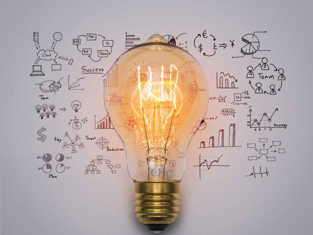 Lâmpada acesa diante de desenhos e gráficos, simbolizando ideias e inovação em projetos de mestrado.