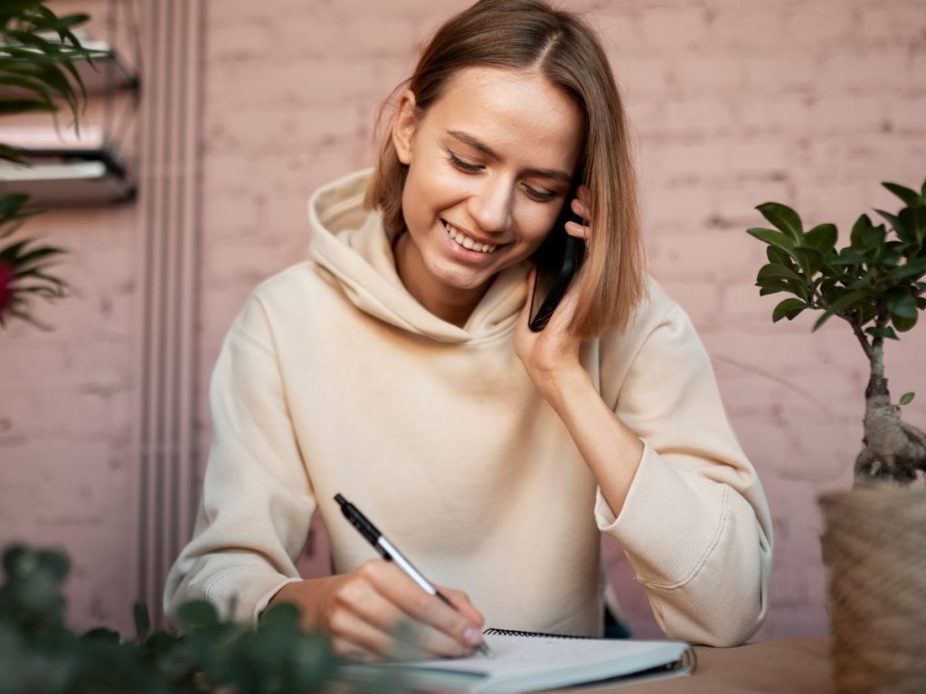 Mulher a consultar um livro e a fazer uma chamada para recolher informações sobre um caso prático.