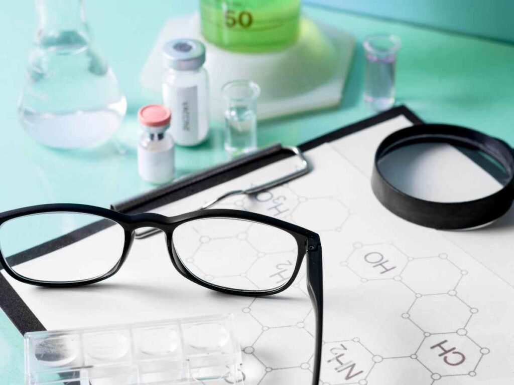 Imagem com microscópio, materiais científicos e um caderno mostrando fórmulas químicas, com o foco no estudo científico.