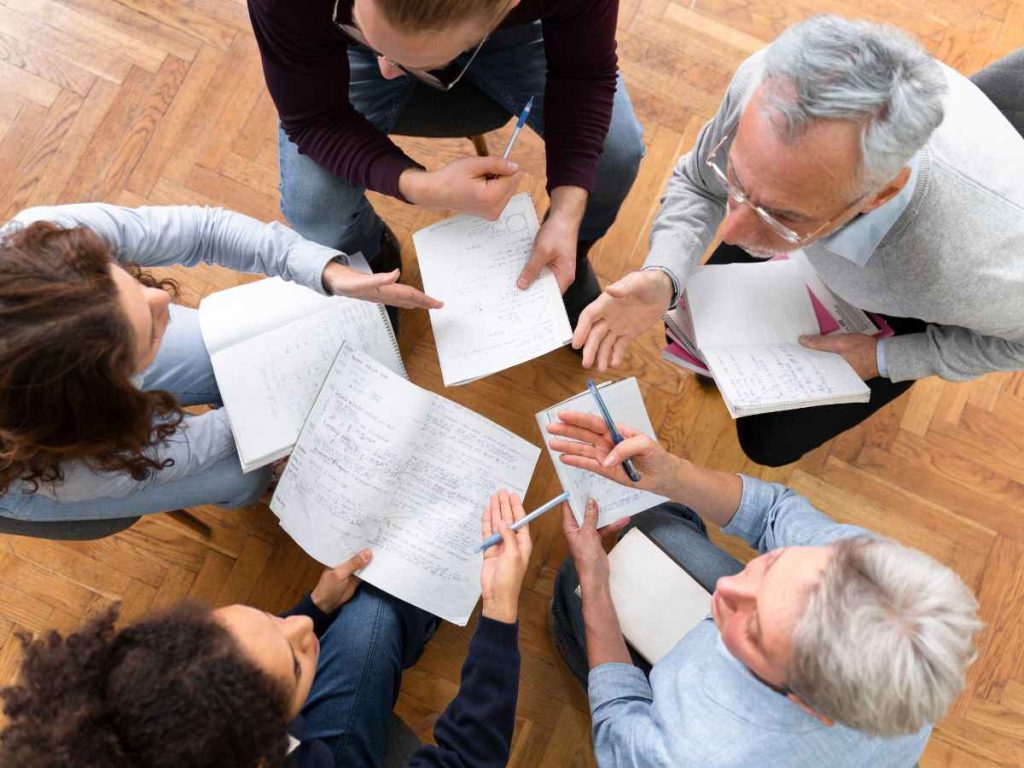 Grupo de pessoas discutindo e anotando ideias para um projeto acadêmico.